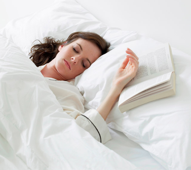 Female sleeping next to book in bed