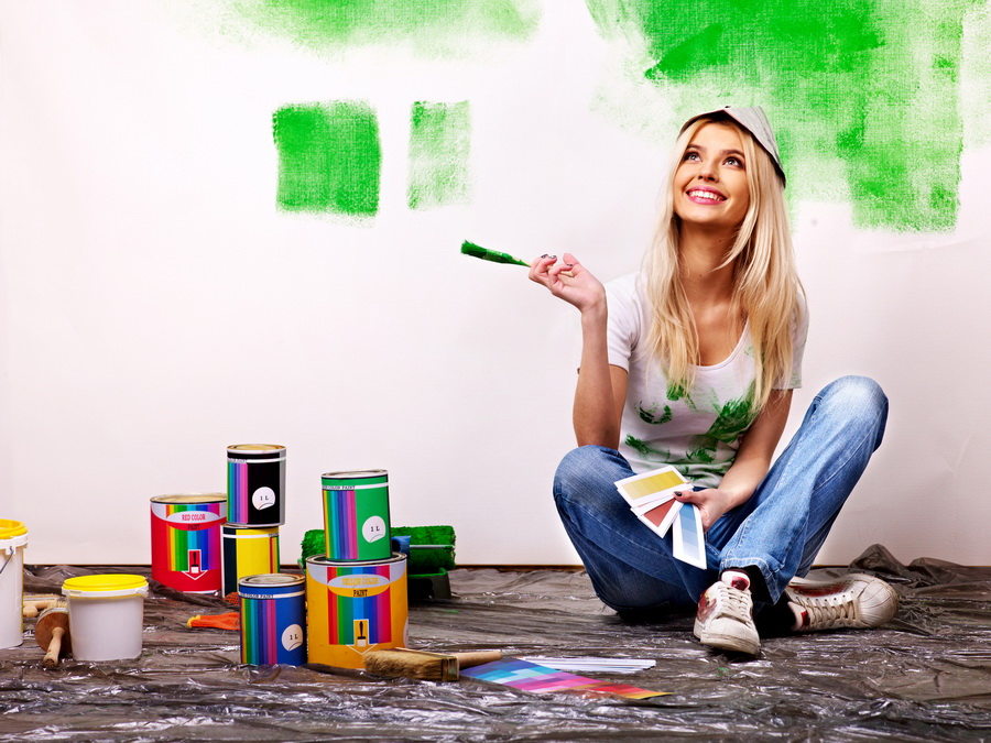 Woman paint wall at home.